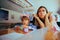 Mother Covering Ear Sitting in a Loud Restaurant with her Child