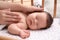 Mother covering her sleeping baby with blanket in crib at home