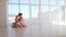 Mother cuddling with daughter sitting on the floor in dance studio