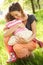 Mother Cuddling Young Daughter In Summer Field