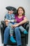 Mother and cute child dressed in pirate and police costume sitting on motherÂ´s knee in black armchair.