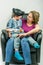 Mother and cute child dressed in pirate and police costume sitting on motherÂ´s knee in black armchair.