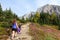 A mother and daugher hiking a beautiful trail above the treeline with a huge mountain in the background during a sunny fall day