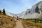 A mother and daugher hiking a beautiful trail above the treeline with a huge mountain in the background during a sunny fall day