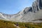 A mother and daugher hiking a beautiful trail above the treeline with a huge mountain in the background during a sunny fall day