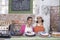 Mother And Daughter In Aprons Standing At Cake Shop Counter