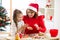 Mother and daughter baking Christmas cookies at decorated tree. Mom and child bake Xmas sweets. Family with kids