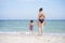 Mother daughter beach together rear view Unrecognizable caucasian woman little girl swimwear standing seaside back