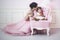 Mother and daughter a beautiful and happy pink interior with vintage chair and balls in beautiful dresses