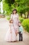 Mother with daughter in beige lush dresses and son in a green shirt are in the summer green park, a woman with two children