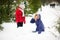 Mother with daughter build a snowman in park.