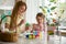 A mother and daughter celebrating Easter, painting eggs with brush