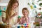 A mother and daughter celebrating Easter, painting eggs with brush