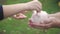 Mother and daughter child putting coins into piggy bank. Woman holds piggy bank while girl puts coins inside outdoor