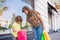 Mother and daughter on a city street with shopping bags, sunny day. Happy shopping with smiles