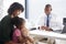 Mother And Daughter In Consultation With Doctor In Office