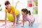 Mother and daughter doing fitness exercises on mat at home.