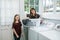 A mother and daughter doing laundry chores together in their natural light laundry room