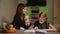 Mother and daughter doing a school homework assignment, a little boy watches it. Brother helps to do homework.