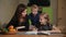 Mother and daughter doing a school homework assignment, a little boy watches it. Brother helps to do homework.