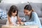 Mother and daughter drawing together sitting in living room