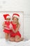 Mother and daughter dressed as Santa with gift, snow