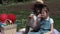 Mother and daughter drinking juice in a park during a picnic