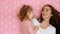 Mother and daughter embrace, smiles, have fun, laugh and kissed. Close-up portrait young woman and her child on pink