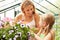 Mother And Daughter Growing Plants In Greenhouse