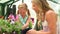 Mother And Daughter Growing Plants In Greenhouse