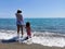 Mother and daughter hand in hand with bare feet in front of the beach with copy space