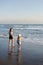 Mother with daughter have fun at beach with black sand in Bali, running at waves, enjoy life and traveling.