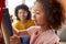 Mother And Daughter Having Fun Drawing Picture On Whiteboard At Home Together