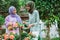 mother and daughter in headscarves chatting while spraying flower plants