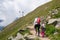 Mother and daughter hiking hand in hand a trail through mountain pastures.