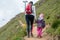 Mother and daughter hiking hand in hand a trail through mountain pastures.