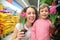 Mother and daughter hold pots with flowers in shop