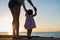 Mother and daughter holding hands, watching the sunset together on a beach.