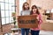 Mother and daughter holding welcome doormat in shock face, looking skeptical and sarcastic, surprised with open mouth