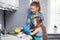 Mother and daughter at home in the kitchen washing dishes