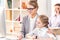 Mother and daughter hugging and looking on monitor in business office, father behind