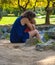 Mother and daughter hugging relaxing in Turin park with their feet in creek