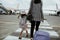 A mother and daughter join hands walking with a suitcase