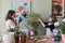 Mother and daughter kid care together for house flower in pot, girl sprinkles spray on plant