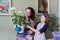 Mother and daughter kid care together for house flower in pot, girl sprinkles spray on plant