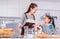 Mother and daughter learning to bake and book from online tutorial on Computer laptop at home