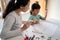 Mother and daughter learning to read and write letter at home