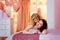 Mother and daughter lie in bed in the pink bedroom and dressing room. The daughter kisses her mother. They enjoy socializing and