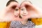 Mother and daughter looking through heart shaped love symbol hand gesture. Family, love, togetherness concept. Happy Mother`s Day.