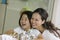 Mother And Daughter Looking At Reflection In Bathroom Mirror